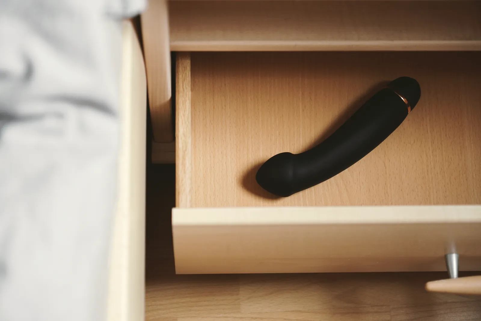 A matte black product in a wooden bedside drawer.